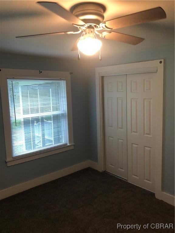 271 Bendall Ln, Mathews, VA 23109 - unfurnished bedroom featuring multiple windows, a closet, dark carpet, and ceiling fan