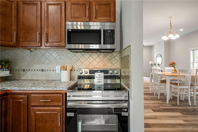2502 4th Ave, Richmond, VA 23222 - kitchen featuring appliances with stainless steel finishes, wood finished floors, decorative backsplash, a chandelier, and brown cabinetry