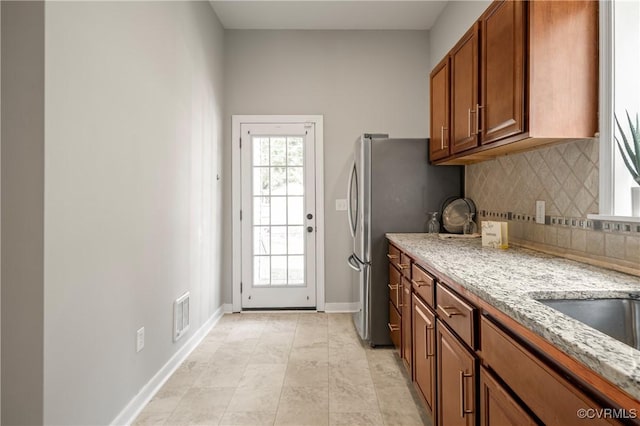 2502 4th Ave, Richmond, VA 23222 - kitchen with backsplash, brown cabinets, light stone countertops, and freestanding refrigerator