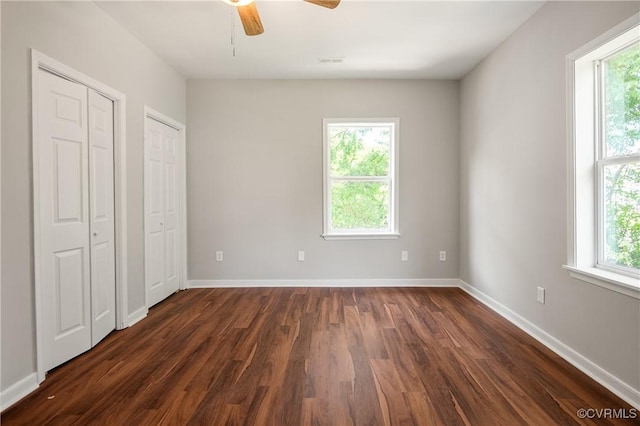 2502 4th Ave, Richmond, VA 23222 - unfurnished bedroom with multiple windows, multiple closets, dark wood-style flooring, and a ceiling fan