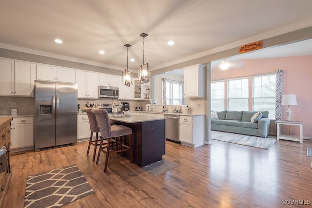 9545 Thornecrest Dr, Mechanicsville, VA 23116 - kitchen with appliances with stainless steel finishes, ornamental molding, a kitchen bar, white cabinetry, and a kitchen island
