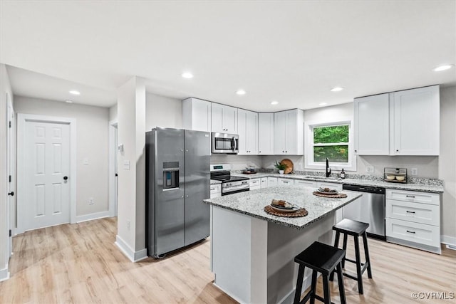 487 Deep Landing Rd, Tappahannock, VA 22560 - kitchen featuring stainless steel appliances, light wood-style floors, light stone counters, white cabinets, and a kitchen breakfast bar
