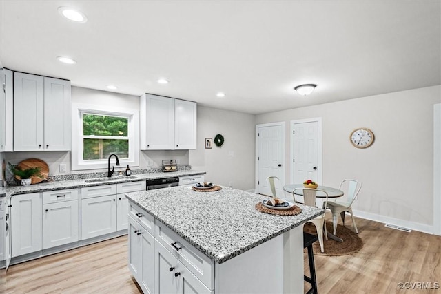 487 Deep Landing Rd, Tappahannock, VA 22560 - kitchen with a center island, light wood finished floors, light stone countertops, a kitchen breakfast bar, and white cabinetry