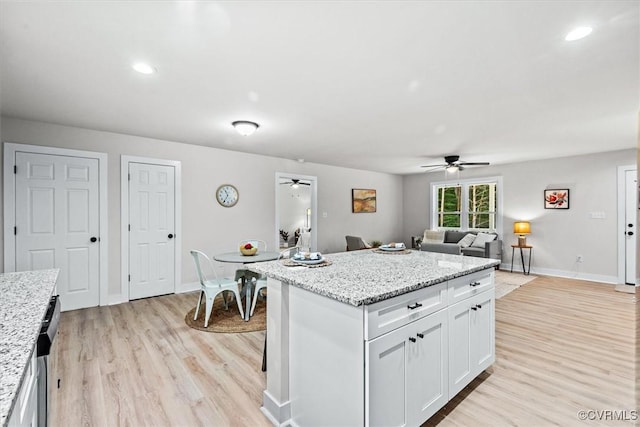 487 Deep Landing Rd, Tappahannock, VA 22560 - kitchen featuring a ceiling fan, light wood-style flooring, white cabinetry, a kitchen island, and light stone counters