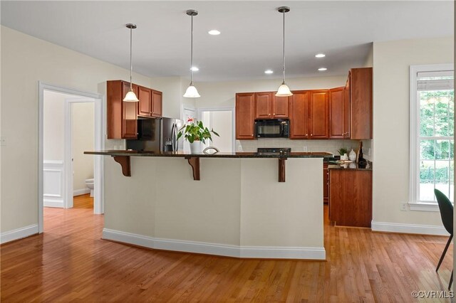 4313 Nevil Bend Turn, Moseley, VA 23120 - kitchen with black microwave, stainless steel fridge, dark countertops, light wood-style flooring, and decorative backsplash