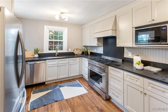 1217 Forest Ave, Henrico, VA 23229 - kitchen with appliances with stainless steel finishes, custom range hood, light wood finished floors, and dark countertops