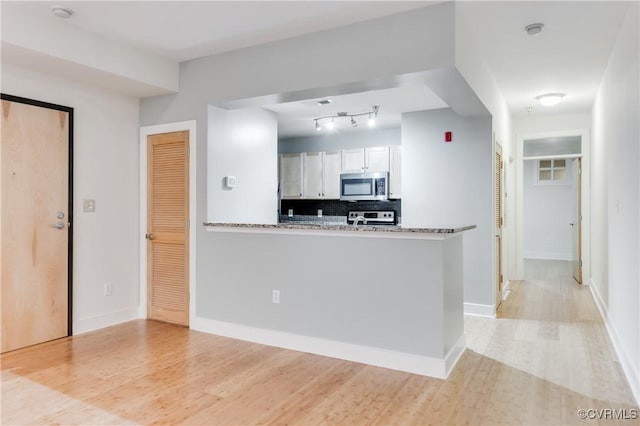 110 W Marshall St Unit U25, Richmond, VA 23220 - kitchen with stainless steel appliances, white cabinets, decorative backsplash, light wood-style floors, and track lighting