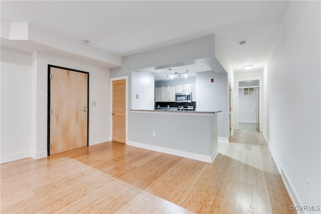 110 W Marshall St Unit U25, Richmond, VA 23220 - kitchen featuring stainless steel microwave, white cabinets, track lighting, backsplash, and light wood-style floors