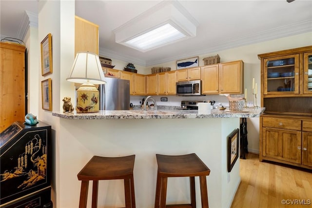 818 Krim Point Loop, Midlothian, VA 23114 - kitchen featuring stainless steel appliances, a breakfast bar, a peninsula, light stone countertops, and light wood finished floors