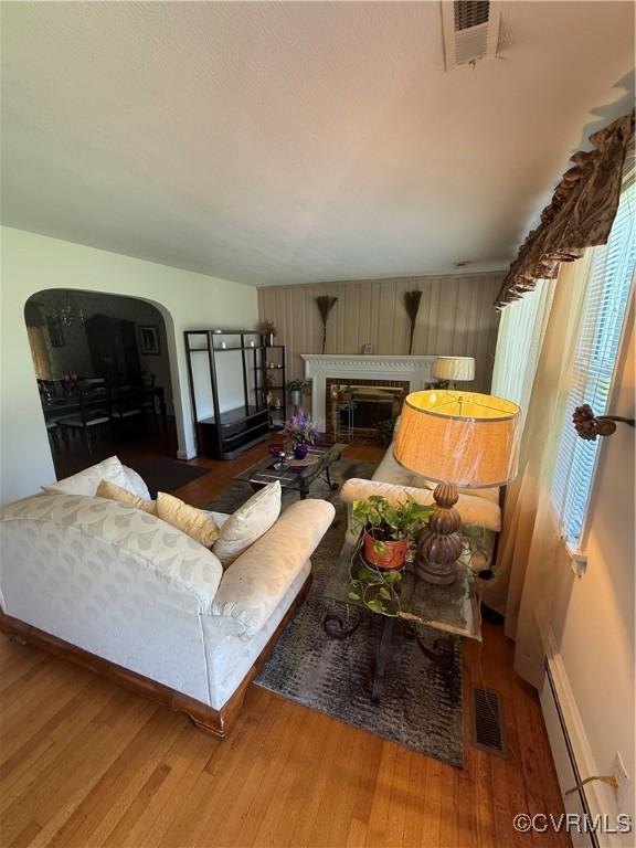 305 Danray Dr, Henrico, VA 23227 - living room with baseboard heating, arched walkways, wood finished floors, and a glass covered fireplace