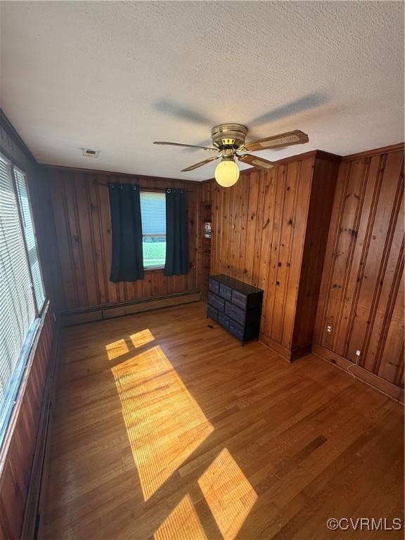 305 Danray Dr, Henrico, VA 23227 - unfurnished living room featuring wood finished floors, wooden walls, baseboard heating, a textured ceiling, and ceiling fan