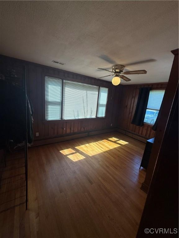305 Danray Dr, Henrico, VA 23227 - unfurnished room featuring a textured ceiling, wood finished floors, a ceiling fan, baseboard heating, and wood walls