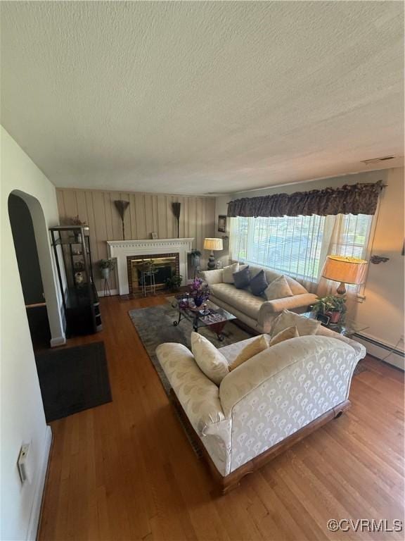 305 Danray Dr, Henrico, VA 23227 - living room featuring a textured ceiling, wood finished floors, a baseboard heating unit, a fireplace with flush hearth, and arched walkways