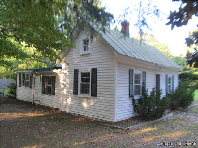 6847 Williams Landing Rd, Hayes, VA 23072 - view of home's exterior featuring a chimney, a standing seam roof, and a metal roof