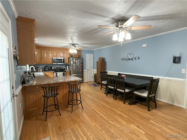 6197 Fishermans Way, Mechanicsville, VA 23116 - kitchen with appliances with stainless steel finishes, brown cabinetry, ceiling fan, a peninsula, and light wood-style flooring