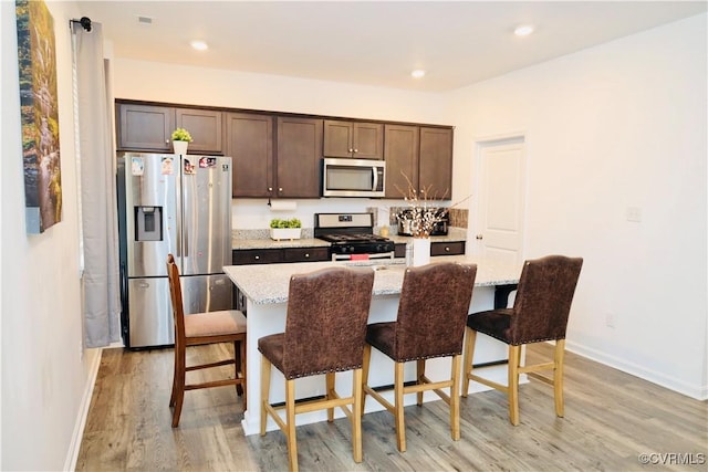 6431 Faulkner Dr, North Chesterfield, VA 23234 - kitchen featuring appliances with stainless steel finishes, light wood-type flooring, dark brown cabinets, a breakfast bar area, and recessed lighting