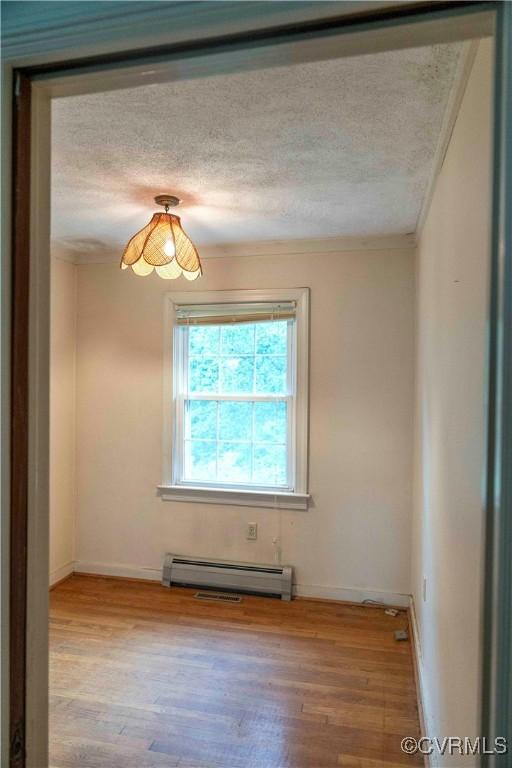 1208 Amesbury Ln, Richmond, VA 23227 - spare room with baseboard heating, a textured ceiling, wood finished floors, and crown molding