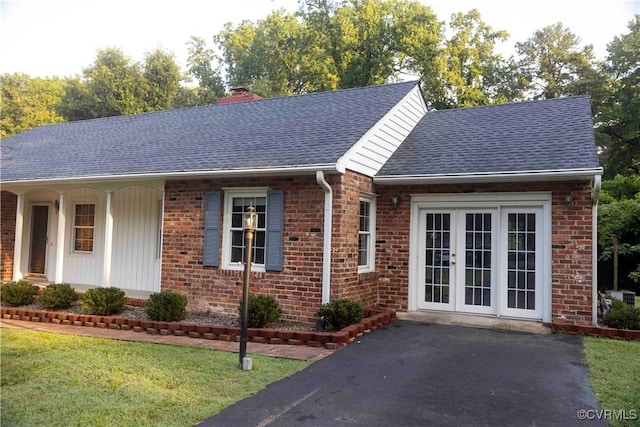 1208 Amesbury Ln, Richmond, VA 23227 - view of front facade with roof with shingles, brick siding, a chimney, french doors, and a front yard