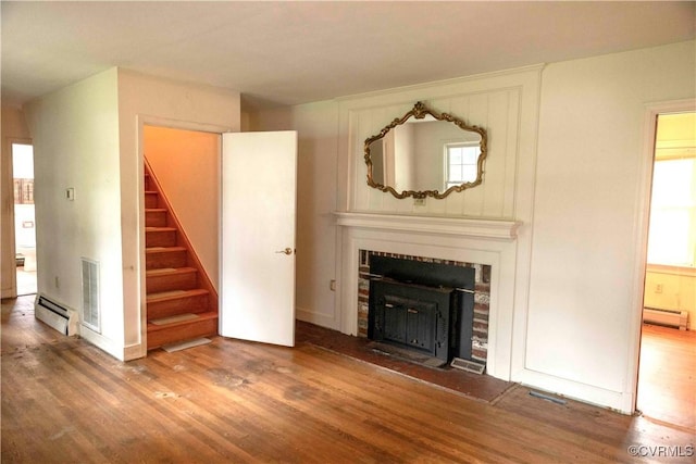 1208 Amesbury Ln, Richmond, VA 23227 - unfurnished living room with wood finished floors, a baseboard heating unit, stairs, a tile fireplace, and plenty of natural light