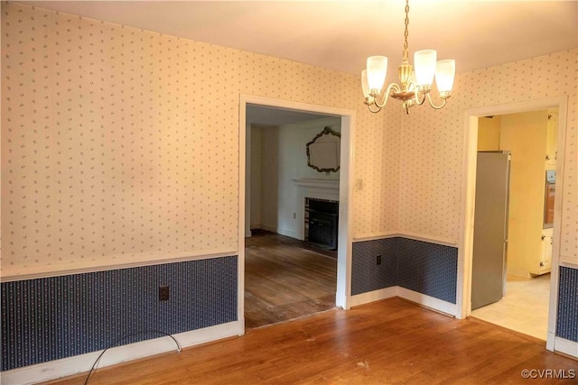 1208 Amesbury Ln, Richmond, VA 23227 - empty room with wallpapered walls, a chandelier, wood finished floors, a fireplace, and radiator heating unit