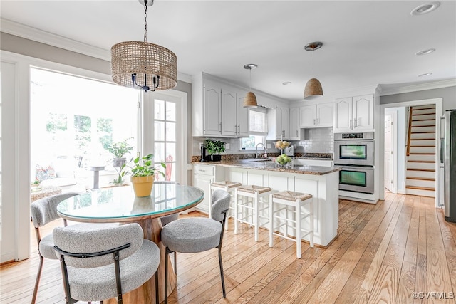 105 Williamson Ct, Henrico, VA 23229 - kitchen featuring appliances with stainless steel finishes, a peninsula, light wood finished floors, a chandelier, and crown molding