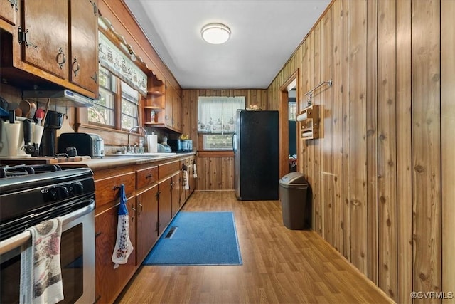 3614 Madison St, Prince George, VA 23860 - kitchen featuring stainless steel appliances, light wood-style flooring, brown cabinets, wood walls, and light countertops