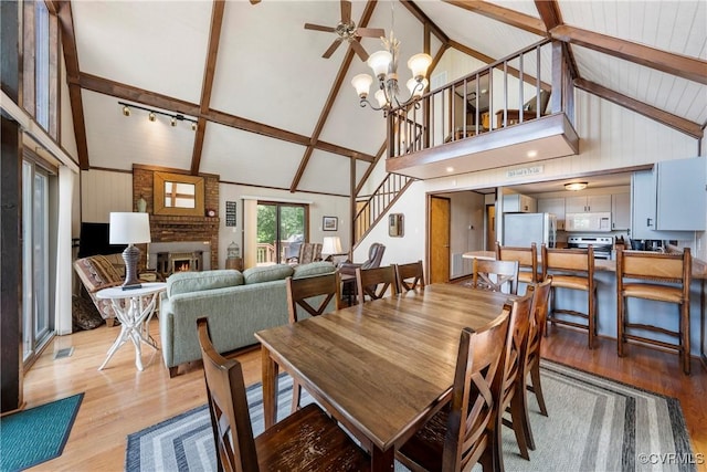 6131 Kellys Gln, Mineral, VA 23117 - dining space with high vaulted ceiling, stairway, light wood-style flooring, a brick fireplace, and a chandelier