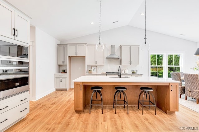9157 Terroir Ln, New Kent, VA 23124 - kitchen with wall chimney exhaust hood, black microwave, light countertops, decorative backsplash, and a kitchen breakfast bar