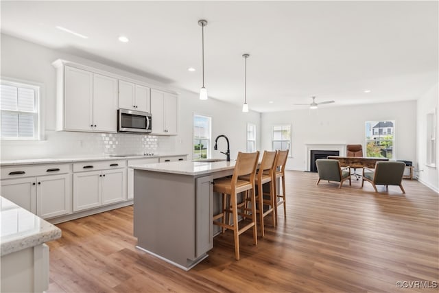 9130 Terroir Ln, New Kent, VA 23124 - kitchen with stainless steel microwave, recessed lighting, light wood-style floors, decorative backsplash, and white cabinets