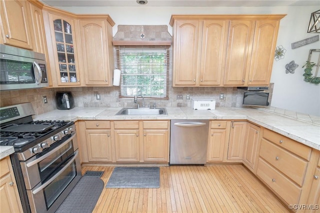 13813 Bluff Ridge Dr, Chesterfield, VA 23838 - kitchen featuring stainless steel appliances, light brown cabinetry, decorative backsplash, and glass insert cabinets