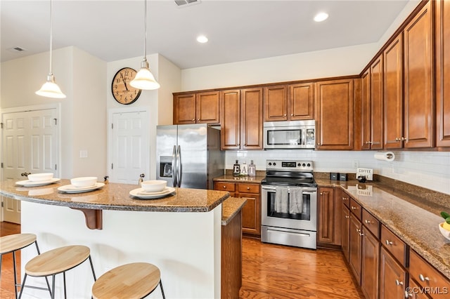 5915 E Stonepath Garden Dr, Chester, VA 23831 - kitchen featuring stainless steel appliances, a breakfast bar, brown cabinets, and recessed lighting