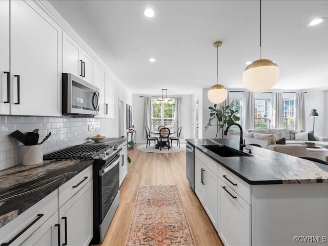 9913 Craftsbury Dr, Midlothian, VA 23112 - kitchen featuring appliances with stainless steel finishes, light wood-style floors, dark countertops, an island with sink, and backsplash
