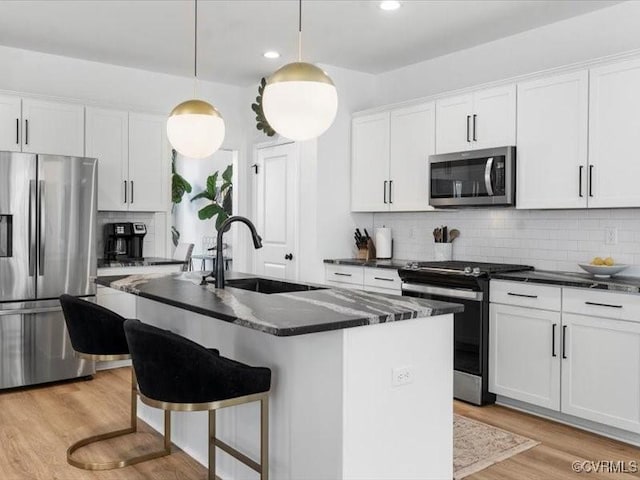 9913 Craftsbury Dr, Midlothian, VA 23112 - kitchen featuring stainless steel appliances, light wood finished floors, backsplash, an island with sink, and white cabinets