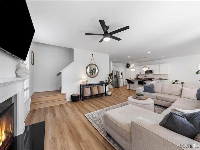 9913 Craftsbury Dr, Midlothian, VA 23112 - living area with a warm lit fireplace, ceiling fan, light wood-type flooring, stairway, and recessed lighting