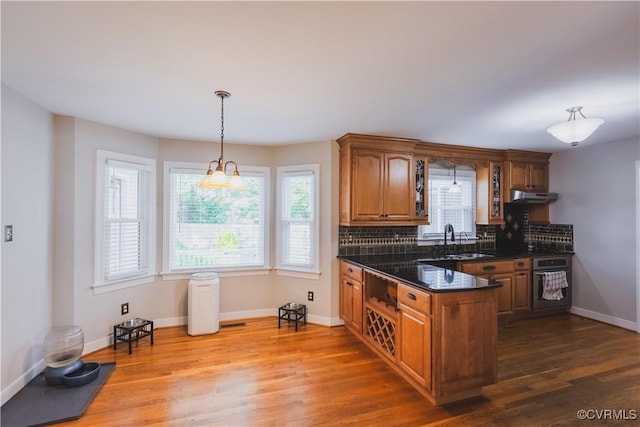 12703 Kelsey Pointe Ct, Chester, VA 23831 - kitchen featuring stainless steel oven, under cabinet range hood, brown cabinets, dark countertops, and tasteful backsplash