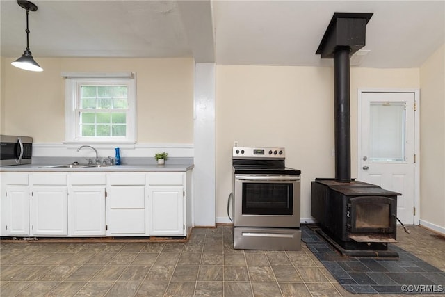 9349 Quinnford Blvd, Chesterfield, VA 23237 - kitchen featuring stainless steel appliances, a wood stove, white cabinetry, hanging light fixtures, and light countertops