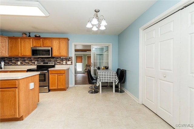 12226 Bristle Cone Ln, Ruther Glen, VA 22546 - kitchen featuring appliances with stainless steel finishes, light floors, light countertops, a chandelier, and brown cabinetry