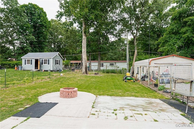 12226 Bristle Cone Ln, Ruther Glen, VA 22546 - view of grassy yard featuring an outdoor structure, a fire pit, a patio, and view of scattered trees