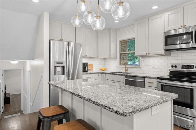 1101 Clearlake Rd, Chesterfield, VA 23236 - kitchen with stainless steel appliances, a breakfast bar, a kitchen island, tasteful backsplash, and light stone counters