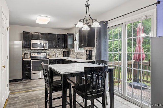 225 Scotch Pine Dr, Sandston, VA 23150 - kitchen with appliances with stainless steel finishes, decorative backsplash, light countertops, a chandelier, and light wood finished floors