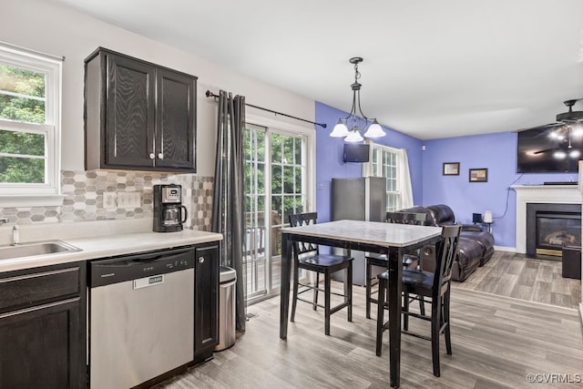 225 Scotch Pine Dr, Sandston, VA 23150 - kitchen featuring dishwasher, light wood finished floors, a chandelier, light countertops, and a glass covered fireplace