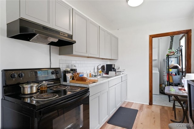 1403 Miles Ave, Hopewell, VA 23860 - kitchen featuring black electric range oven, under cabinet range hood, light wood-style flooring, backsplash, and washer / clothes dryer
