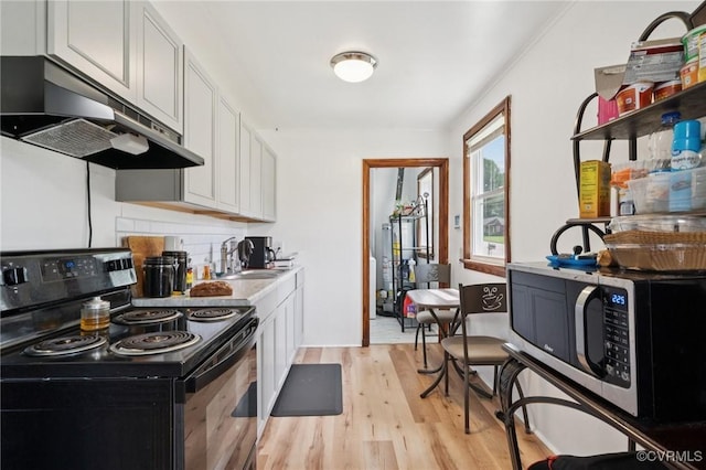 1403 Miles Ave, Hopewell, VA 23860 - kitchen featuring black electric range oven, under cabinet range hood, stainless steel microwave, light wood-type flooring, and gas water heater