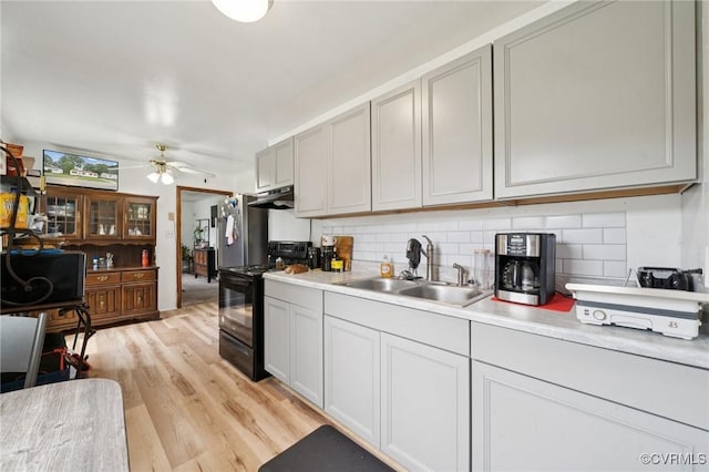 1403 Miles Ave, Hopewell, VA 23860 - kitchen featuring black / electric stove, under cabinet range hood, decorative backsplash, light countertops, and light wood finished floors