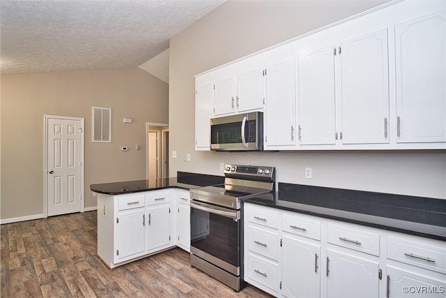 6434 Anderson Hwy, Powhatan, VA 23139 - kitchen featuring appliances with stainless steel finishes, a peninsula, vaulted ceiling, white cabinets, and dark countertops