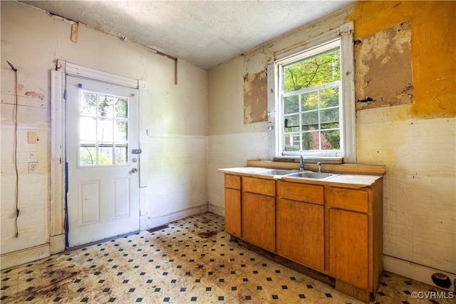 415 W 24th St, Richmond, VA 23225 - kitchen with light flooring, brown cabinetry, light countertops, a textured ceiling, and a wainscoted wall