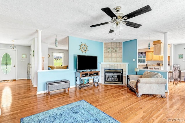 1382 Glebe Landing Rd, Center Cross, VA 22437 - living room with light wood-style flooring, a textured ceiling, ceiling fan, and a tiled fireplace