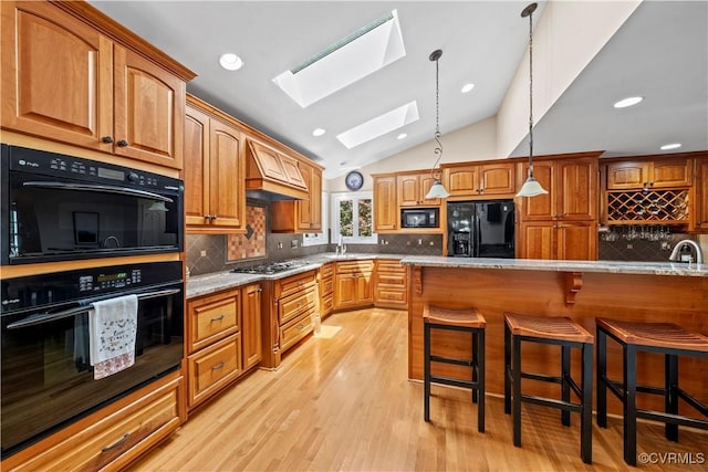 18030 W County Line Rd, Midlothian, VA 23112 - kitchen featuring black appliances, a skylight, a kitchen breakfast bar, vaulted ceiling, and decorative backsplash