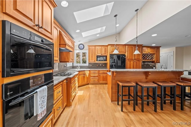 18030 W County Line Rd, Midlothian, VA 23112 - kitchen with black appliances, a skylight, lofted ceiling, a kitchen bar, and light wood-style flooring