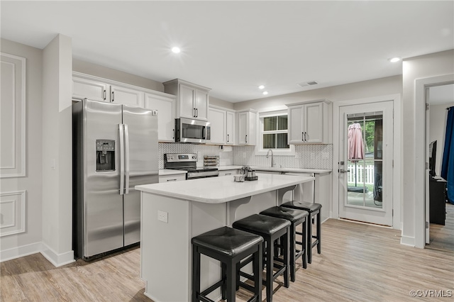 5845 Austin Woods Dr, North Chesterfield, VA 23234 - kitchen featuring appliances with stainless steel finishes, a breakfast bar area, tasteful backsplash, a center island, and light countertops